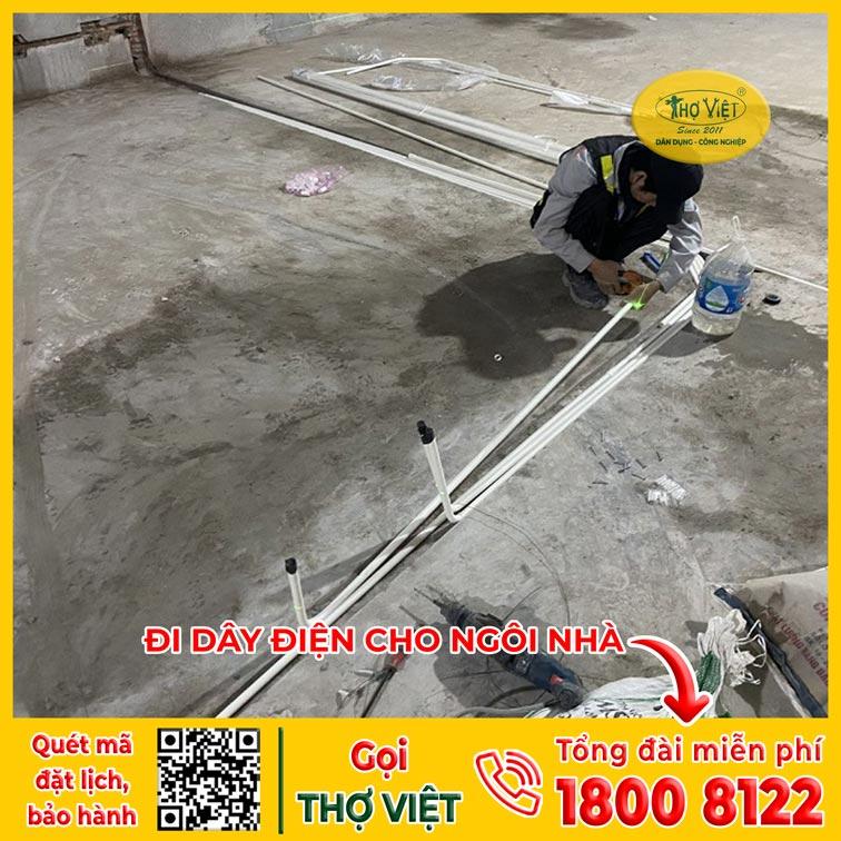 Thợ điện đang lắp đặt ống ruột gà luồn dây điện trên trần nhà
